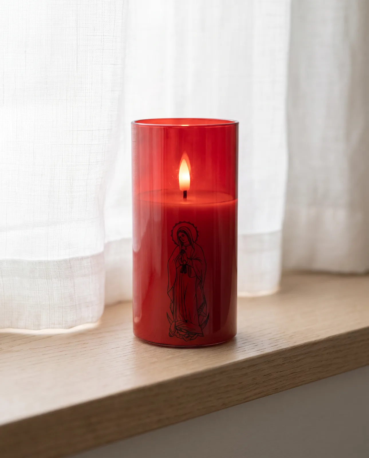 St. Mary candle in red glass on a sunlit windowsill